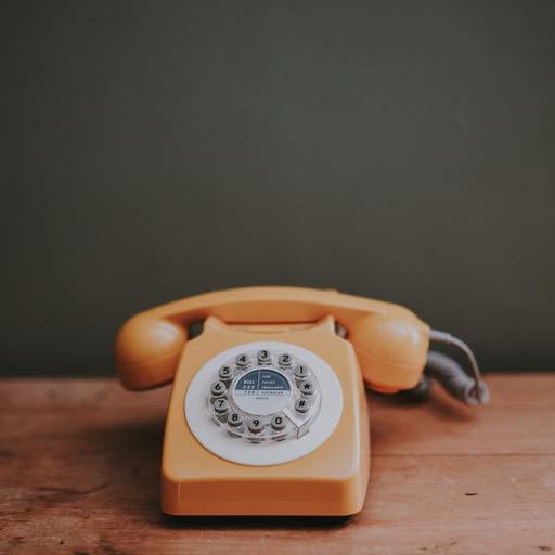 Pomarańczowy telefon z tarczą na drewnianym stole